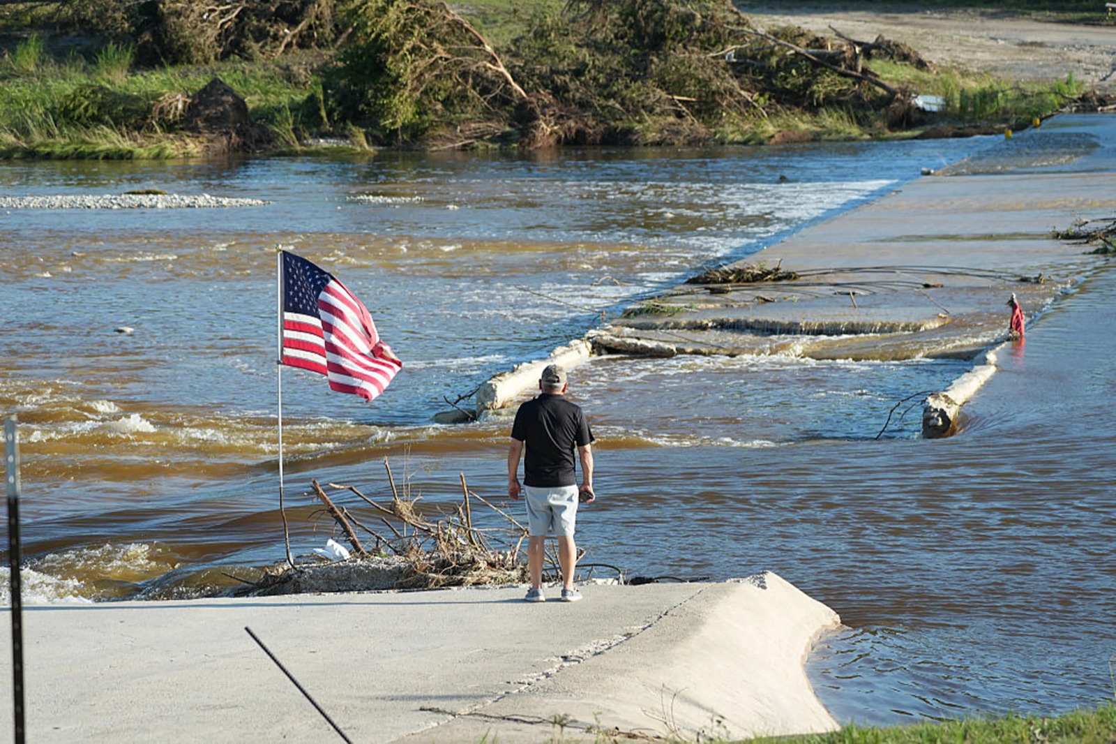 Flooded river crossing with an American flag, the kind of infrastructure Mission monitors